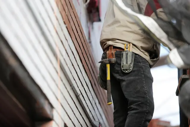 Roofer with a tool belt working on a Hoboken flat roof